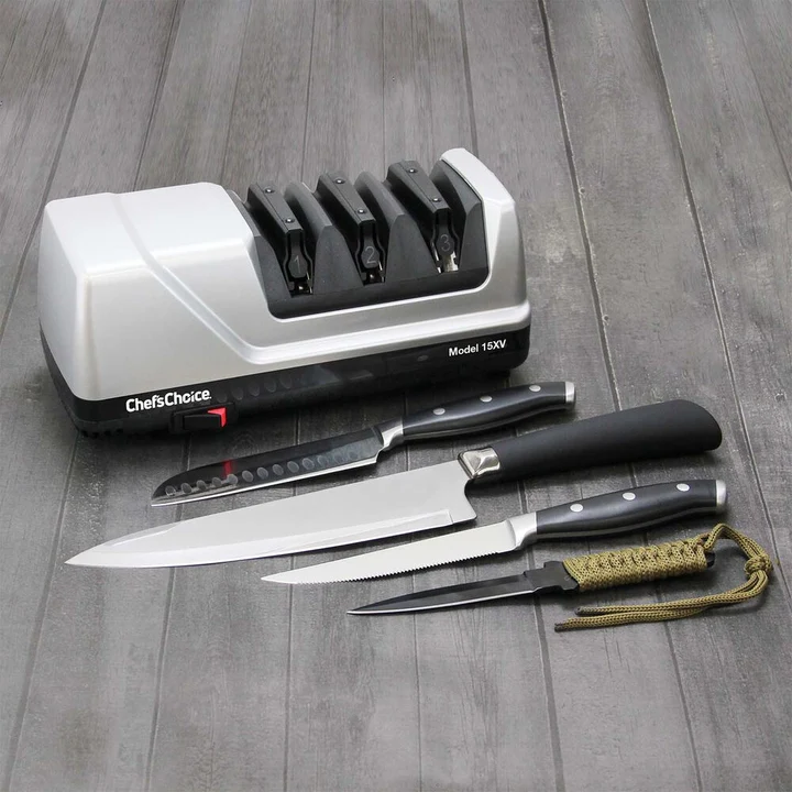 Chef’s Choice Knife Sharpener (Model 15XV) displayed on a wooden surface next to four assorted kitchen and utility knives